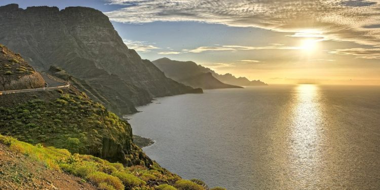 Foto de la carretera que hay a las afueras de Agaete donde se puede ver lo escarpados de los acantilados, el mar y el sol reflejado en el agua