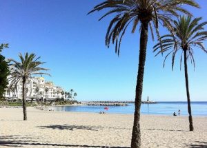 Foto de la playa de Marbella donde se ve lo blanca que es la arena y el mar de fondo