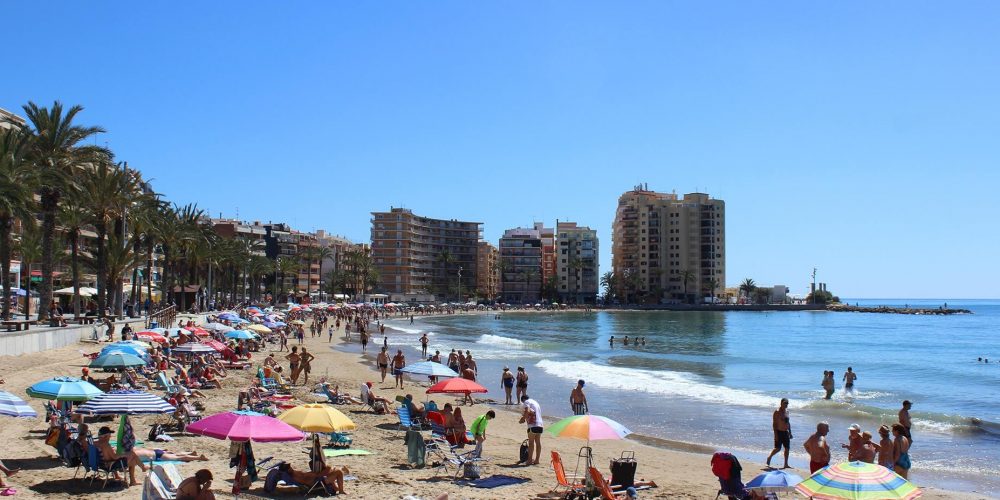 Foto de la playa de Torrevieja un día soleado y con la gente disfrutando del mar con sus sombrillas