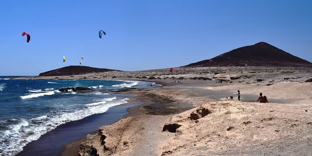 Foto de la playa del Médano con la Montaña Roja al fondo. Lugar perfecto para ir de vacaciones con tu perro