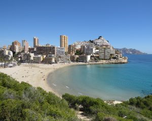 Vista desde la colina de la playa de Cala Finestrat y donde se puede ver el color blanco de la arena, las aguas cristalinas y los apartamentos al fondo