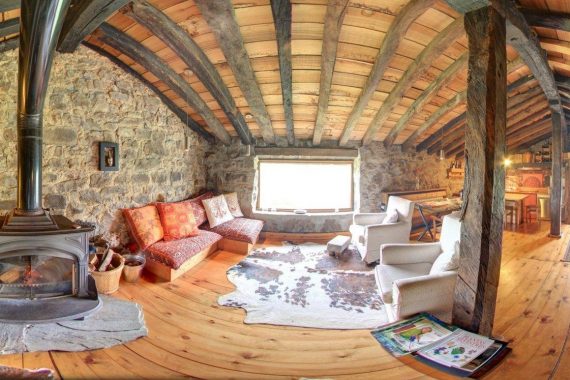 Foto del interior de una cabaña de auténtico lujo con materiales de piedra y madera con chimenea y decoración rústica