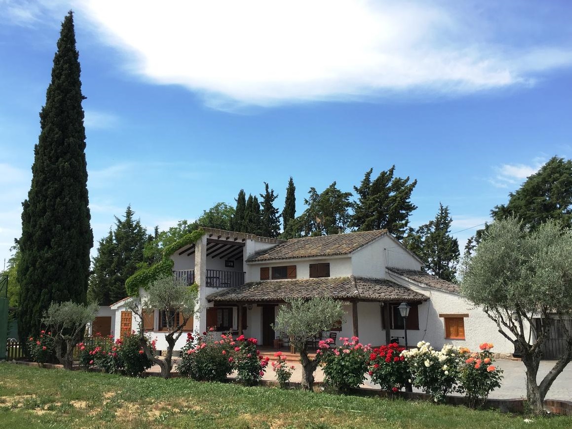 Foto del exterior de la La Casona del Cipres donde se puede ver el cesped y los jardines de esta bonita casa rural que admite perros cerca de Madrid